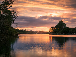 riverside sunrise with cloud reflections