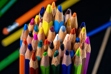 Set of colored colorful wooden pencils on isolated black background. Blue and yellow pencils stand...