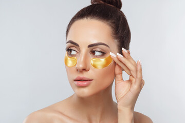 Beautiful woman with healthy perfect skin holds patchs. Beauty face with gold cosmetics collagen hydrogel patch. Lifting anti-wrinkle mask under eyes. Skin care concept.