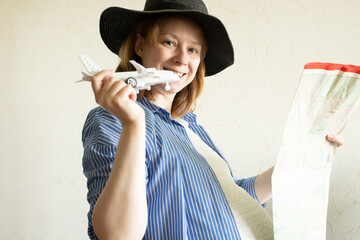 pregnancy and air travel, pregnant woman with a plane and a map in a hat, travel and trips, comfort on board, health care