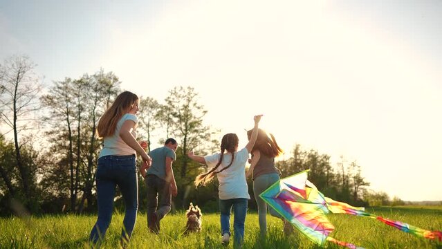 happy family. big family running with a kite. people in the park children child running together in the park at sunset silhouette. mom dad daughter and son are running. concept dream. kids run fun