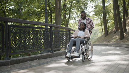 Male friend pushing young woman's wheelchair, life with disability, support