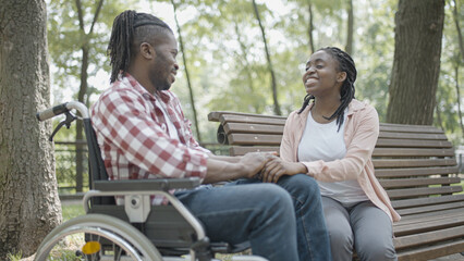 Fototapeta na wymiar Man in wheelchair having fun on date with a young woman, love, relationship