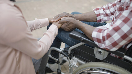 Obraz premium Woman and man in wheelchair holding hands, love and support in a relationship