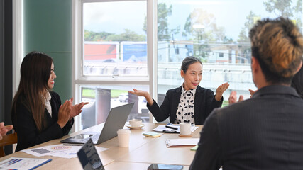 Attractive middle aged female team leader explaining project details, discussing for new strategy of development to diverse employees in meeting