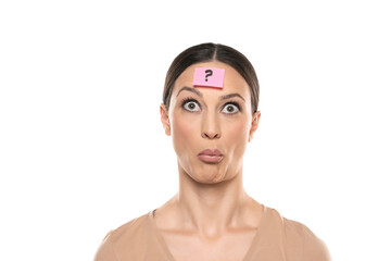 Puzzled young woman with question mark on her foreead on a white studio background
