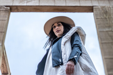 View from below of a woman in warm clothes and hat looking at the camera