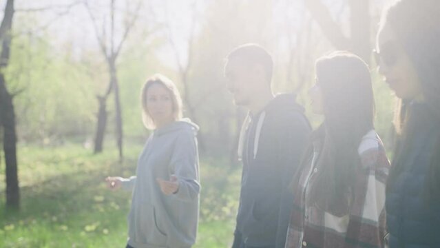 A group of young, successful and beautiful people are walking in the park. Friends met on the day off to discuss gossip.