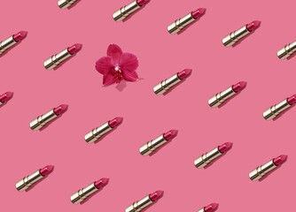 Creative seamless pattern of vivid pink golden lipsticks and orchid flower on bright pink background. Trendy and fashion makeup concept. Natural cosmetics backdrop.