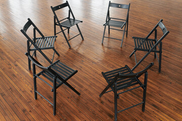 Above angle of six black wooden chairs forming circle on brown floor of office, lecture hall or...