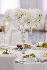 Wedding bouquet in restaurant on the table. White flowers .Element of decor in restaurant. Decoration on wedding. Beautiful and elegant