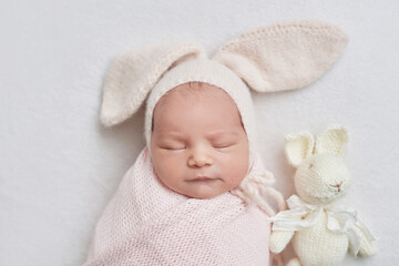 Newborn baby girl in bunny hat. Healthy child. Happy motherhood and parenting