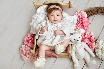 Baby girl with flowers and toys. Postcard Mother's Day and Easter. Children Protection Day. World Happiness Day. Smiling child.