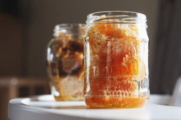 Open glass jars filled with fresh honey in beeswax on white table