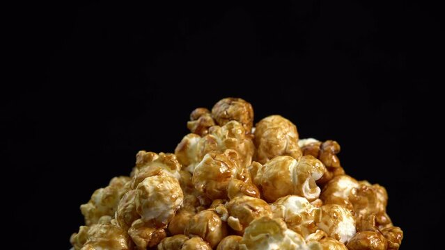 Coffee taste popcorns rotating into the bowl on black background close up. Caramel popcorn. Healthy food for morning breakfast. Healthy breakfast concept. High quality 4k footage