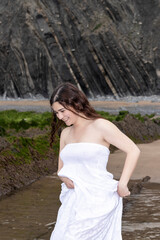 Fototapeta na wymiar brunette woman in white dress laughing on the beach