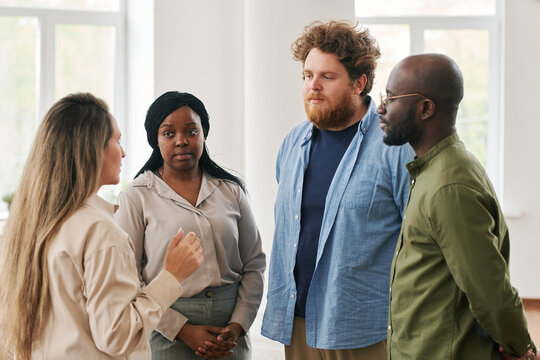 Group of young interracial people discussing their problems and giving advice to one another while attending course of psychological help
