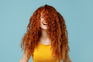 Young overjoyed happy redhead woman 20s wearing yellow t-shirt dance waving fooling around have fun enjoy play fluttering hair isolated on plain light pastel blue background. People lifestyle concept.