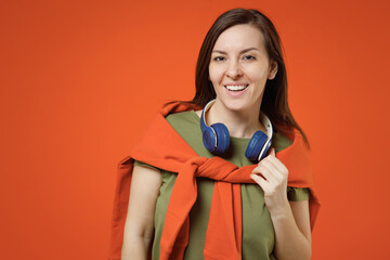 Young smiling happy fun woman 20s wearing khaki t-shirt tied sweater on shoulders headphones listen...