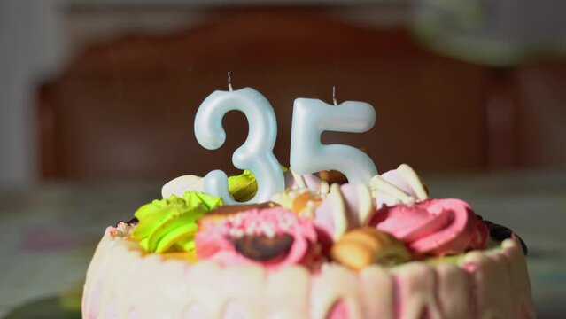 Blowing out candles on a birthday cake. 35th birthday. Birth cake with a burning birth candle. Happy Birthday background anniversary celebration concept. High quality 4k footage
