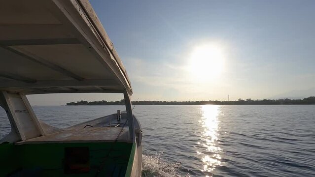 Local wooden boat floating towards the shore during sunset. View from standing inside of boat.