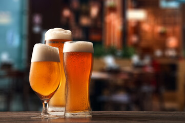 Three different glasses of beer on counter in pub.