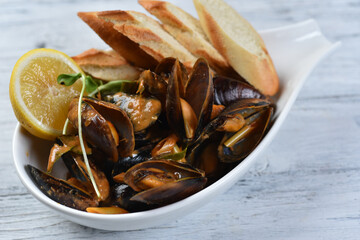 mussels in the shell with sauce, croutons and lemon