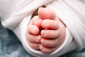 The tiny foot of a newborn. Soft feet of a newborn in a white blanket and on a blue background. Close up of toes, heels and feet of a newborn baby. Studio Macro photography. Woman's happiness