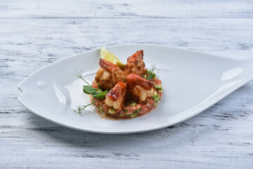 salmon and trout tartare with grilled prawns in sauce, avocado, lemon and sprouts