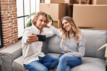 Man and woman couple make selfie by the smartphone sitting on sofa at new home