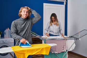 Obraz premium Couple ironing clothes at laundry room stressed and frustrated with hand on head, surprised and angry face