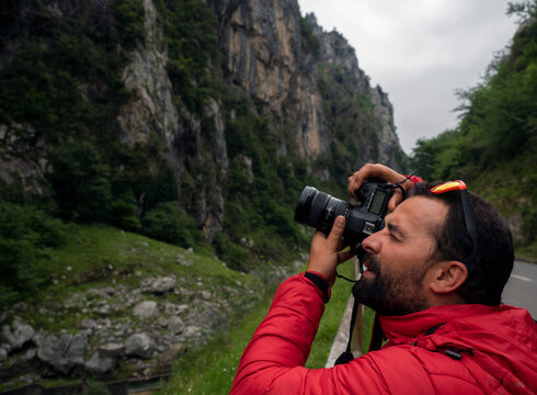 man with camera and red jacket in the mountains