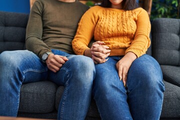 Man and woman couple sitting on sofa with hands together at home