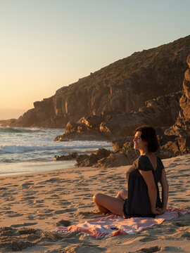 happy woman on the beach watching the sunset and stretching
