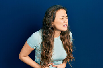 Naklejka premium Young hispanic girl wearing casual clothes with hand on stomach because nausea, painful disease feeling unwell. ache concept.