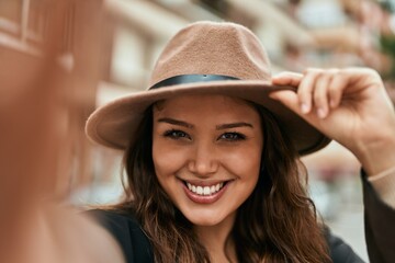 Young hispanic tourist woman smiling happy making selfie by the camera at the city.