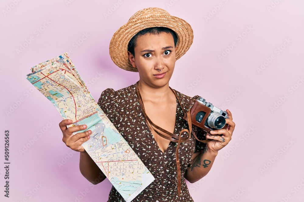 Canvas Prints Beautiful hispanic woman with short hair holding city map and vintage camera clueless and confused expression. doubt concept.