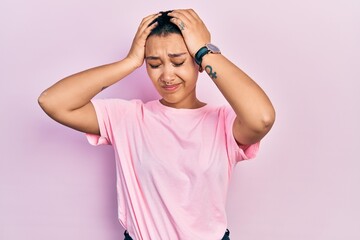 Beautiful hispanic woman with short hair wearing casual pink t shirt suffering from headache desperate and stressed because pain and migraine. hands on head.