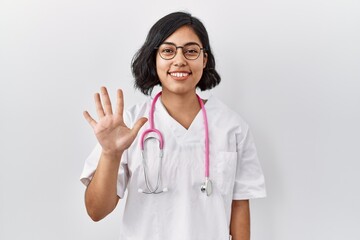Young hispanic doctor woman wearing stethoscope over isolated background showing and pointing up with fingers number five while smiling confident and happy.