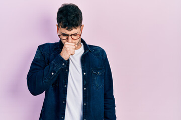 Young hispanic man wearing casual clothes and glasses feeling unwell and coughing as symptom for cold or bronchitis. health care concept.