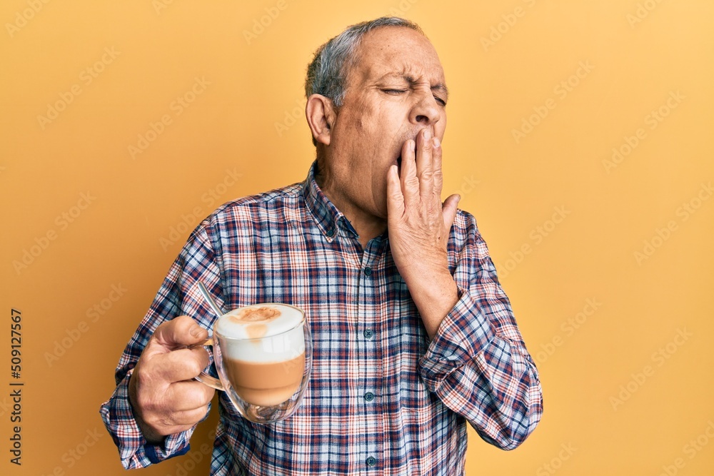 Poster Handsome senior man with grey hair drinking a cup coffee bored yawning tired covering mouth with hand. restless and sleepiness.