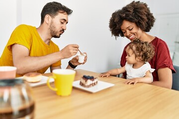Fototapeta na wymiar Couple and daughter having breakfast sitting on table at home