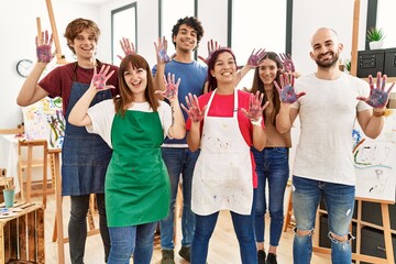 Group of people showing painted palm hands looking to the camera standing at art studio.