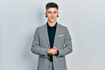 Young caucasian boy with ears dilation wearing business jacket with hands together and crossed...