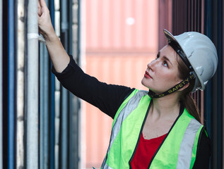 Female foreman worker is inspecting container box at commercial transport dockyard. Beautiful...