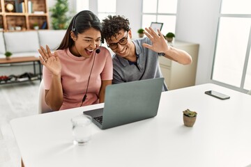 Young latin couple smiling happy having video call using laptop and headset at home.