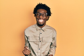 Young african american man wearing casual clothes and glasses very happy and excited doing winner gesture with arms raised, smiling and screaming for success. celebration concept.