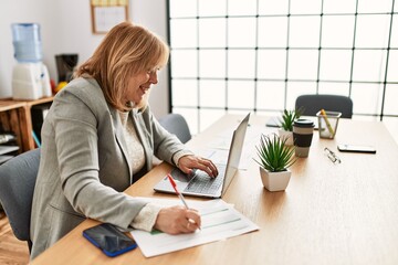 Middle age businesswoman smiling happy working at the office.