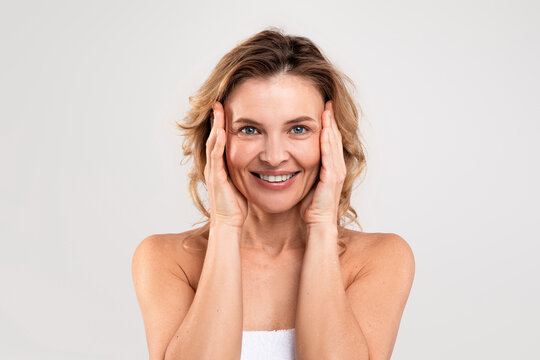 Anti-Aging Skincare. Beautiful Middle Aged Woman Touching Face And Smiling At Camera