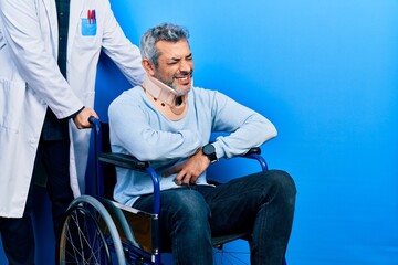 Handsome middle age man with grey hair on wheelchair wearing cervical collar with hand on stomach because nausea, painful disease feeling unwell. ache concept.